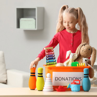 Girl packing up toys and other items into a box ready to donate.