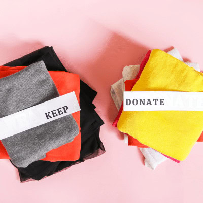 Two piles of folded clothes, one labelled keep the other donate.