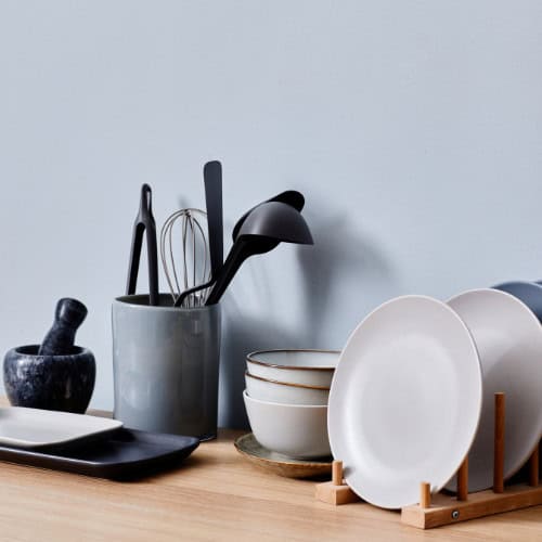 Plates, bowls, utensils on kitchen work surface.